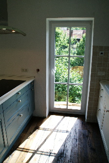 Die rückwärtige Front der Kochinsel ist auch in Blau gehalten.  Und wieder Sonnenstrahlen durch die bodentiefe Türe in der Küche. Schön!